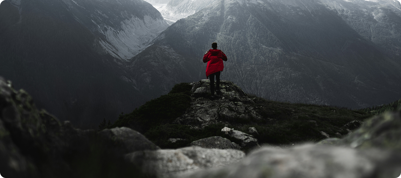Man wearing red rain jacket with a scenic mountain background