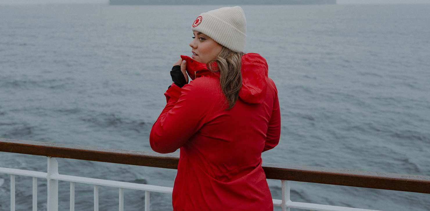 Woman wearing red rain jacket standing on a boat with ocean background