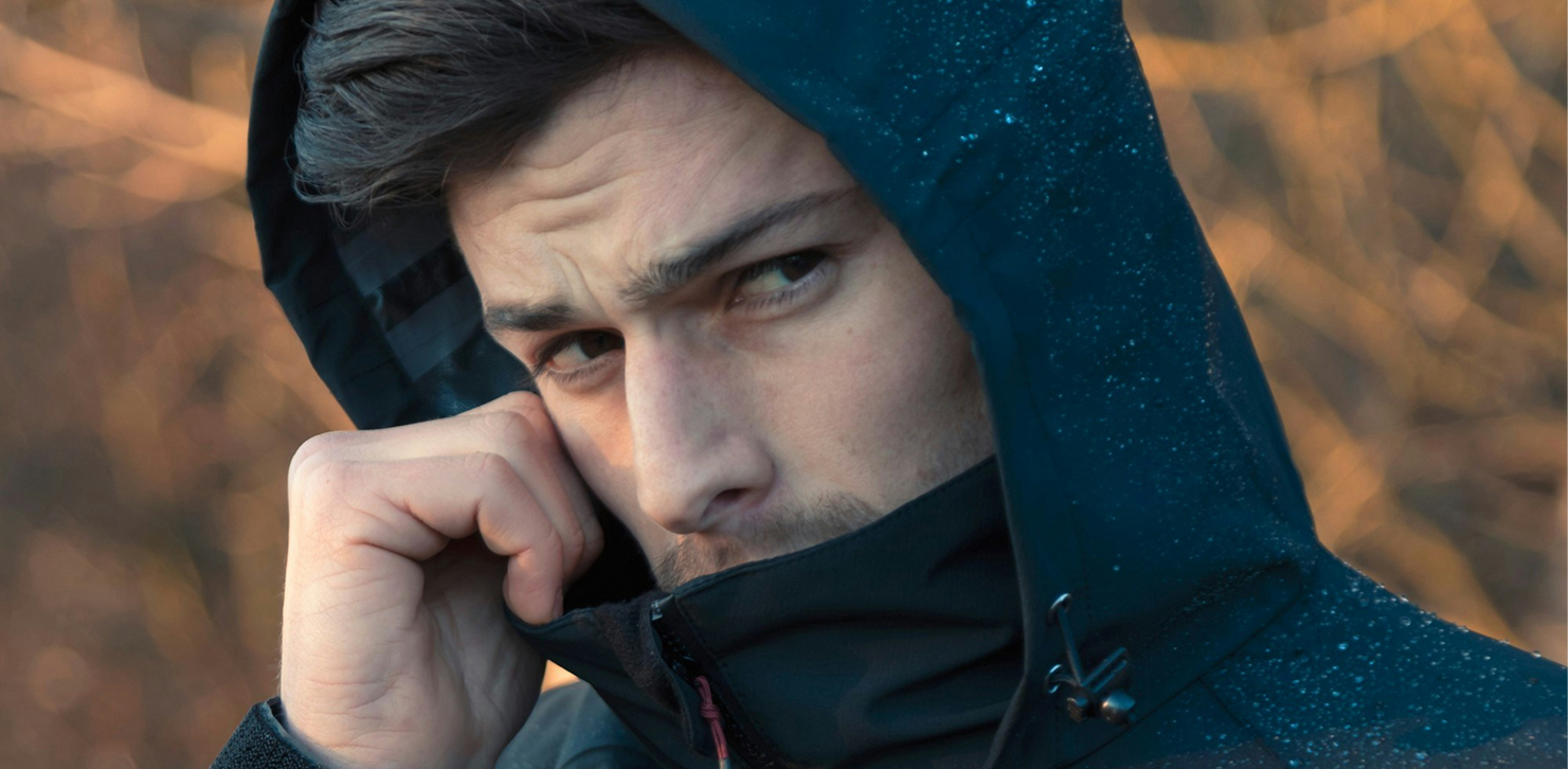 Man wearing black rain jacket with hoodie outdoors