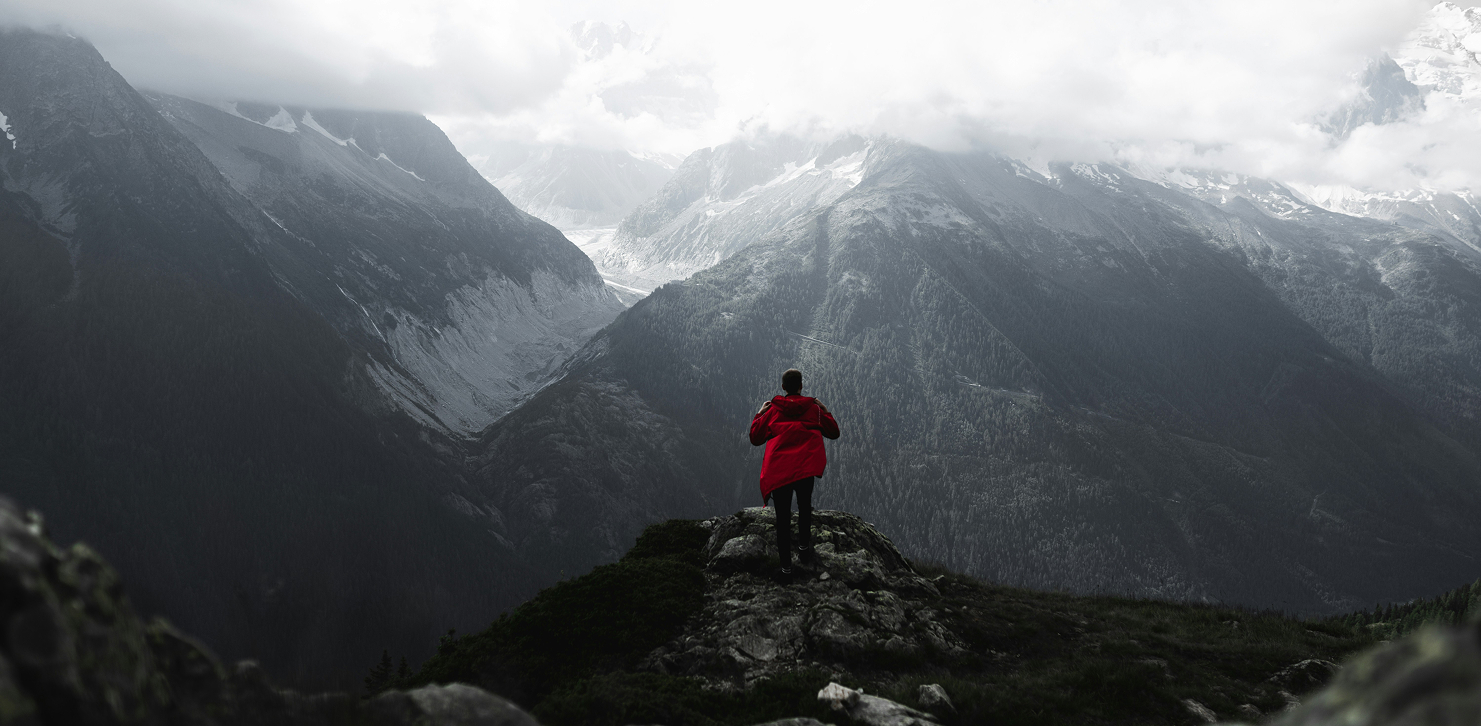 Person wearing red rain jacket with scenic mountain background